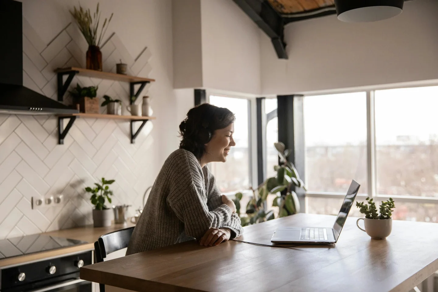 A woman seated at her kitchen table with a laptop